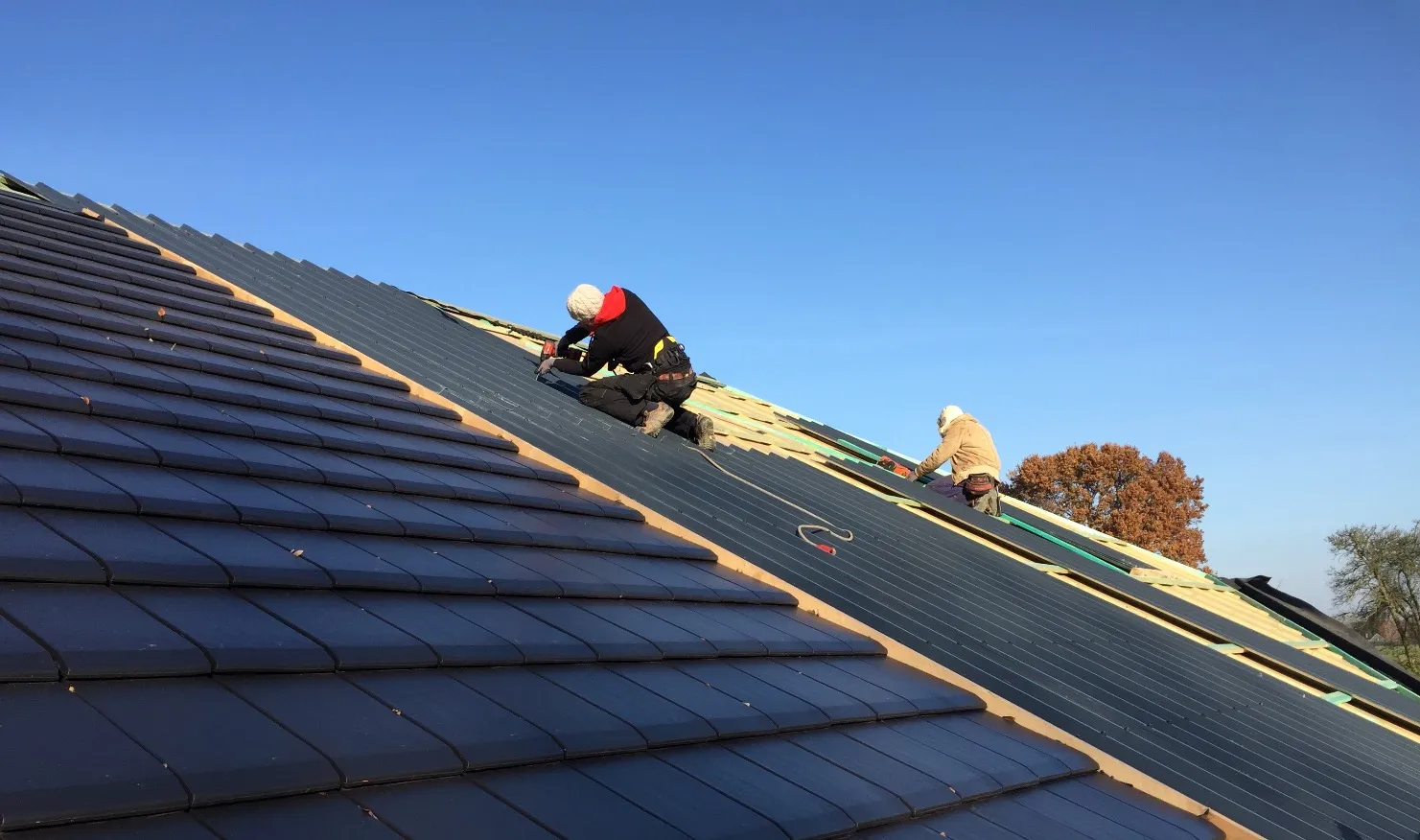 Couvreurs au travail sur une toiture en tuiles anthracite